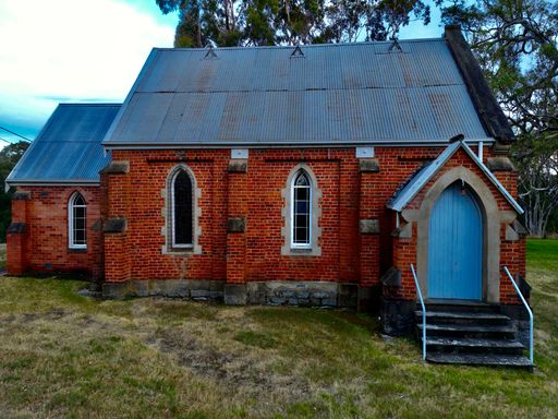 A a red brick house featuring a vibrant blue door situated on a lush green lawn