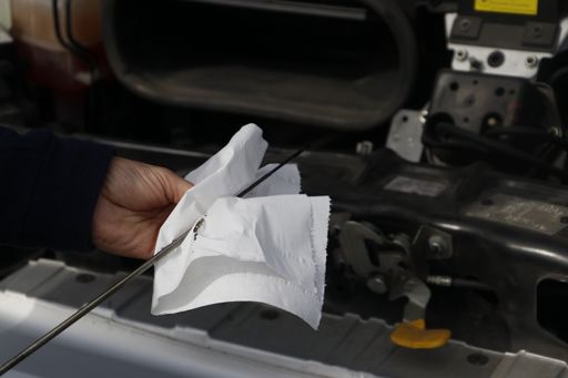 A person using a napkin to check car oil