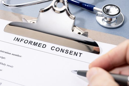 Close up of a Hand filling a Informed Consent form on desk