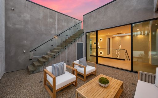 Outdoor patio with wooden furniture and staircase against a clear blue sky