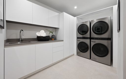 A laundry room showcasing sleek white cabinets, a modern black stove, and a state-of-the-art washer, New Construction Home in Tarzana, California