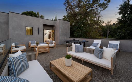 An Outdoor furniture and tables arranged in a serene backyard during daylight hours, New Construction Home in Tarzana, California