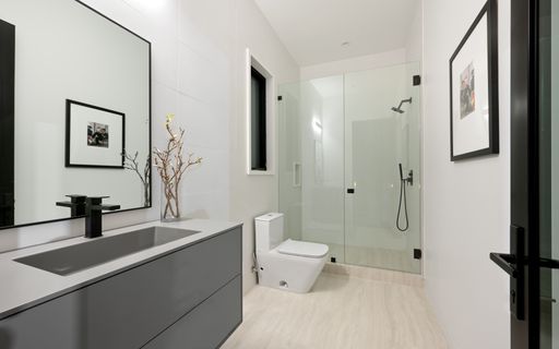 A spacious bathroom featuring a dual sink vanity, modern shower, and toilet, New Construction Home in Tarzana, California