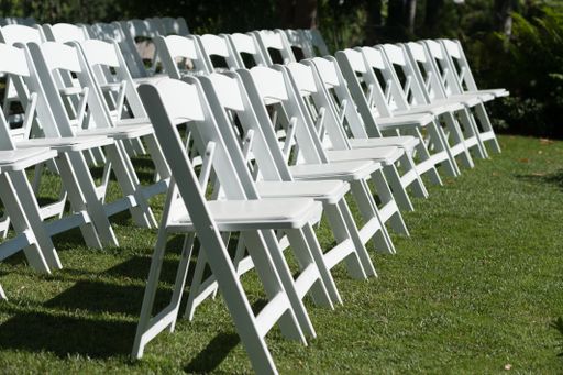 The chairs placed on a green lawn set up for an outdoor wedding ceremony