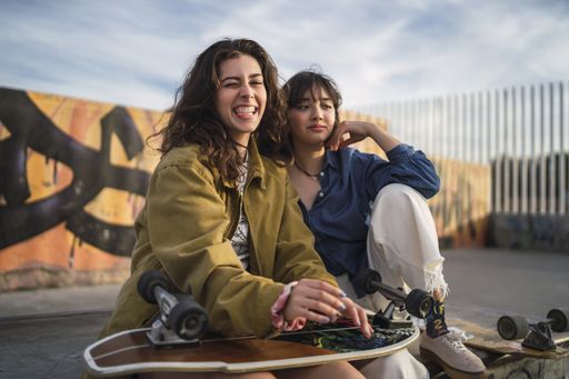 Two girls sitting closely next to each other in a park
