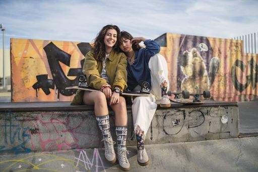 Two girls sitting closely next to each other in a park