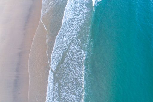 drone overhead view of the shore of a beach with turquoise water