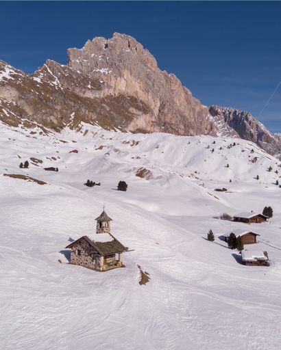 A vertical shot of houses on a steep mountain covered with white snow during winter