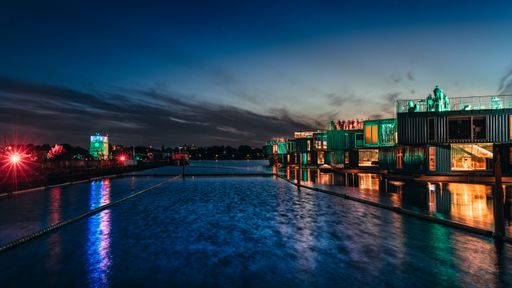 A beautiful night view of people enjoying in bar rooftop near a river in Refshaleoen, Denmark