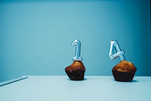 A closeup shot of "1" and "4" candles on cupcakes isolated on a blue background