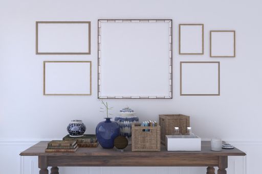 A table with decorative items under a wall with multiple frames