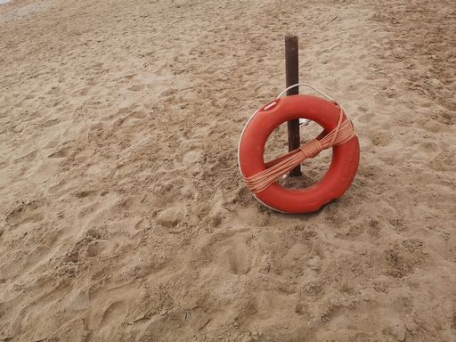 A closeup of a lifebuoy on a beach sand