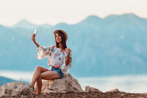 A young Caucasian female taking photos with her cellphone in a park in Montenegro