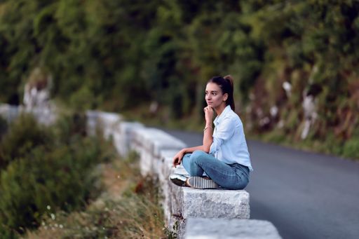 A young Caucasian female sitting by the road and enjoying the nature of Montenegro