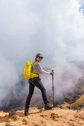 A vertical shot of a happy Mexican girl with a yellow backpack, smiling on the peak of the Iztaccihuatl Volcano