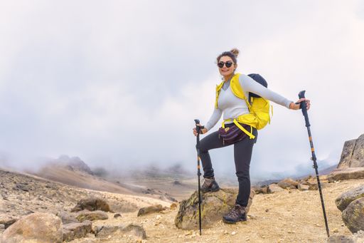 A female hiker with sunglasses and a yellow backpack on the peak of the Iztaccihuatl Volcano in Mexico