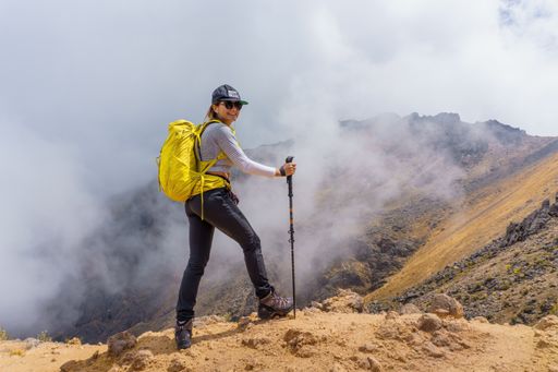 A happy woman with a yellow backpack, smiling after hiking on Iztaccihuatl, Mexico on a foggy day