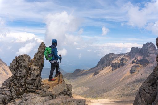 A back view of a hiker with a green backpack on top of the Iztaccihuatl volcano