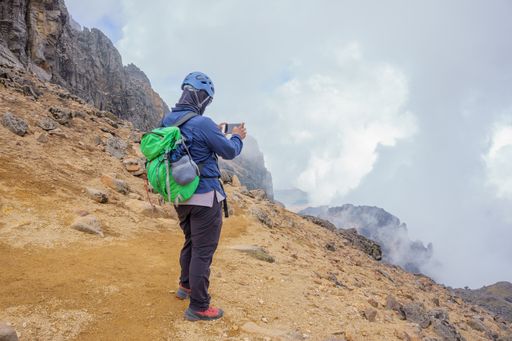 A hiker with a green backpack taking pictures on his phone on Iztaccihuatl volcano