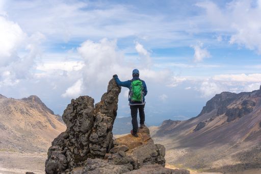 A back view of a hiker with a green backpack on top of the Iztaccihuatl volcano