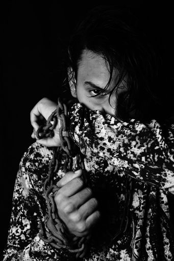 A grayscale shot of a handsome guy posing chained up