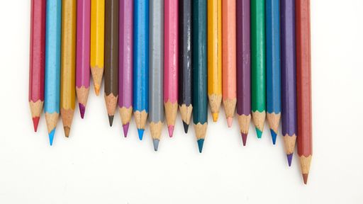 A top view of many colorful pencils on a blank notebook