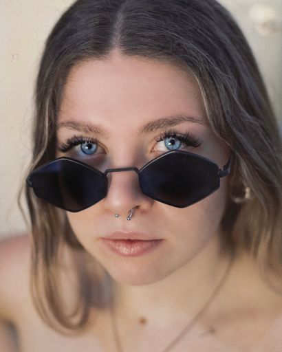 A beautiful shot of a young blue-eyed Spanish woman wearing black sunglasses and nose piercing