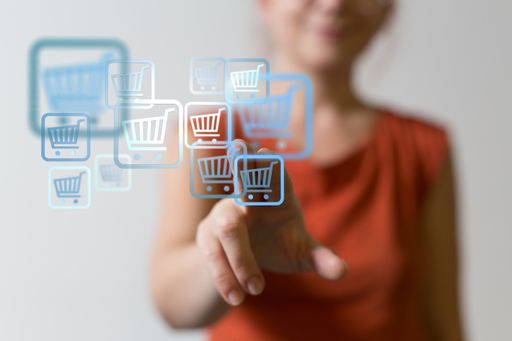 An online shopping concept. Woman clicking on virtual trolley icons to shop online