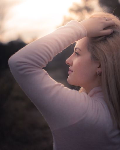 A side-view portrait of a beautiful Hispanic blonde girl looking into the distance at sunset
