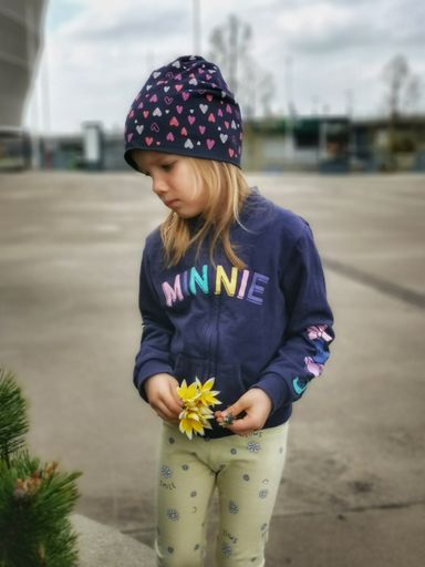 A vertical shot of a Caucasian girl standing outdoors