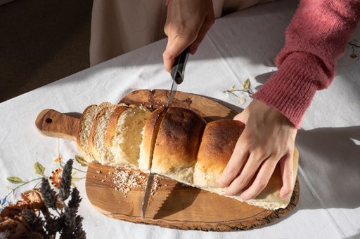A woman cutting bread of hemp seed on a wooden board.
