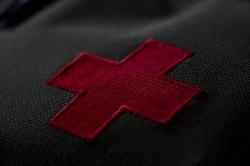 A closeup shot of red cross medic patch on black cloth