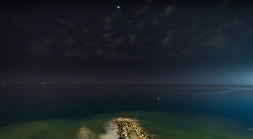 Panoramic view of the Mediterranean Sea at night with the water in long exposure and stars in the sky.
