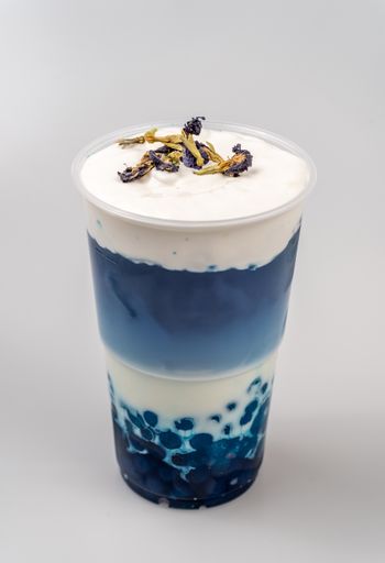 A closeup of a cup of delicious cold blue bubble tea with blue boba and foam on top