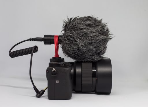A closeup shot of a professional camera and a microphone on a white background