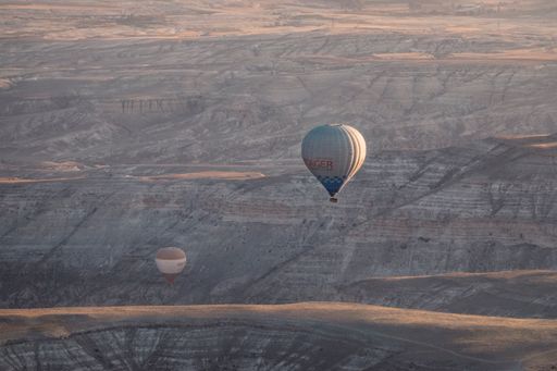 A tranquil scenery of a hot air balloon flying above the rocky mountains in Cappadocia,  Turkey