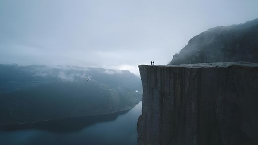 A lone individual standing on a cliff overlooking a serene lake