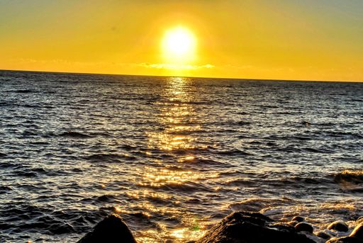 A beautiful sunset scenery with the bright yellow sky over the calm ocean