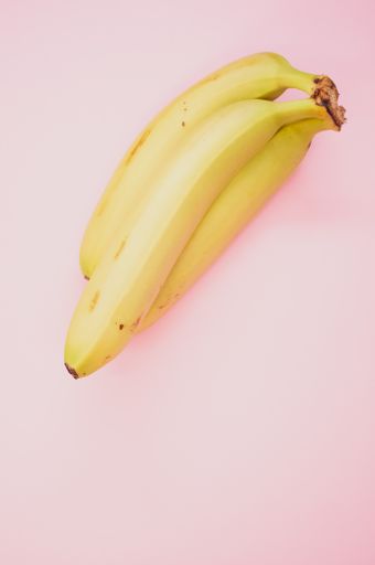 A vertical shot of ripe bananas isolated on pink background