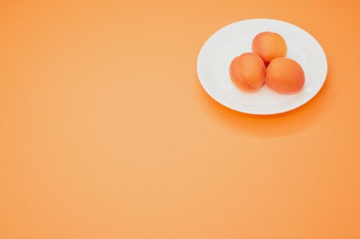 A high angle shot of fresh three apricots isolated on an orange background