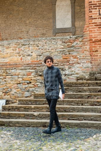 A young Italian man walking with a book in his hand