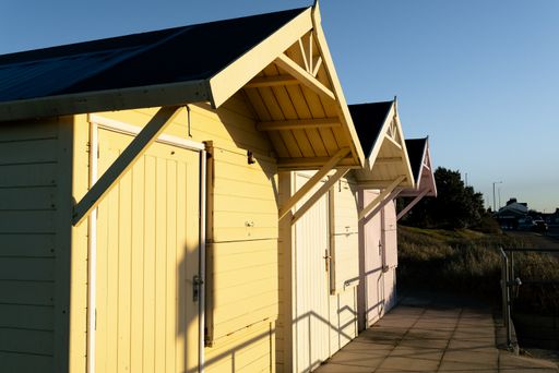 row of wooden beach huts brightly painted in pastel colors at the seaside