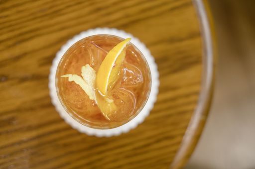 A top view of a refreshing cocktail with ice cubes and orange slice on a wooden table