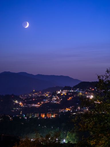 Moon and night sky over town from hilltop