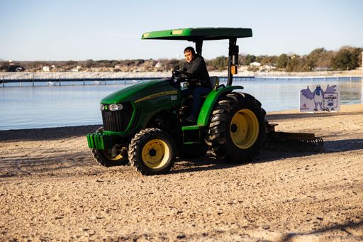 A man operating a tractor on a beach on a sunny day in Granbury, United States