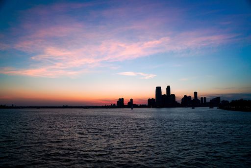 A scenic view of a silhouette of skyscrapers under a beautiful sunset sky