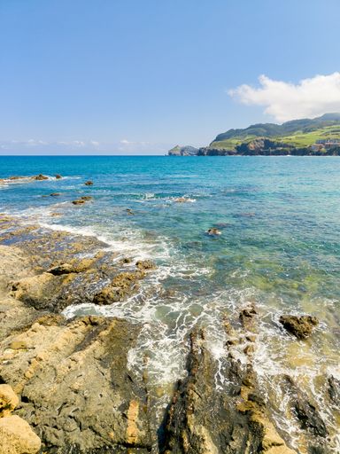 A blissful shot of the sea seen through coastal rocks under the blue sky