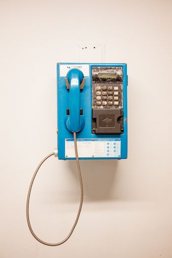 A closeup shot of an old and damaged public telephone on a white wall