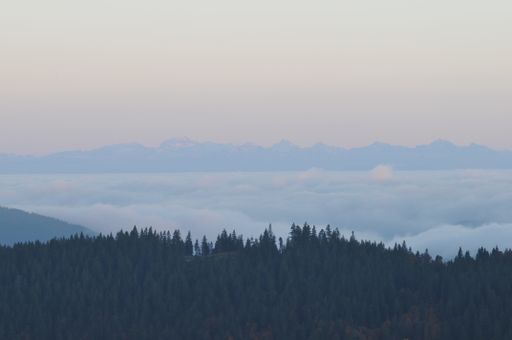 A horizontal wallpaper of beautiful forest mountain above the clouds at sunset