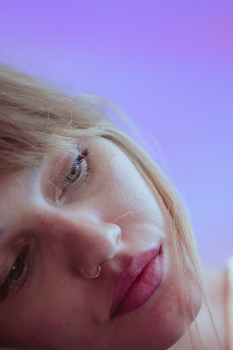 A beautiful Caucasian woman with a nose piercing against a violet background